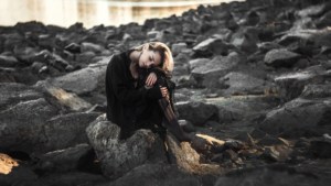 A sad. lonely and perhaps depressed young woman sitting on a beach