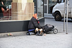 Lady sitting on sidewalk with a cart with her belongings
