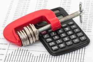 a calculator and coins squeezed down in red clamp