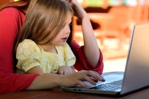 Mom with toddler on lap working laptop