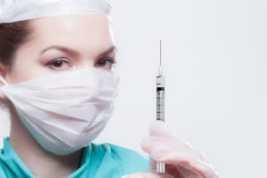 Nurse with mask holding a syringe