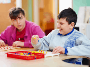 2 developmentally handicapped youth at table working on puzzles and peg boards