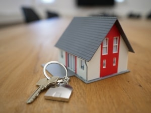 Tiny modle house beside keys on table