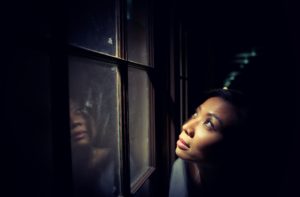 women alone in dark looking through window