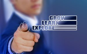 A man in a suit pointing at the words grow, learn and explore