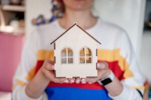 A young woman holding up a model of a house front