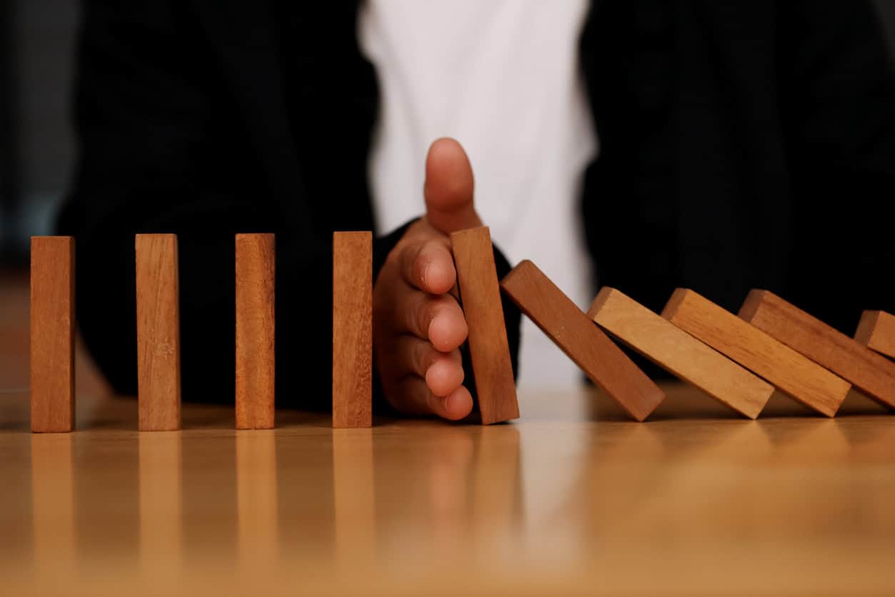 Businesswoman stops a chain fall like domino game. Concept of preventing crisis and failure in business.