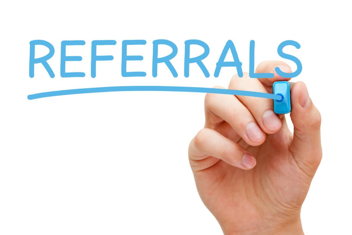 Hand writing Referrals with blue marker on transparent wipe board.