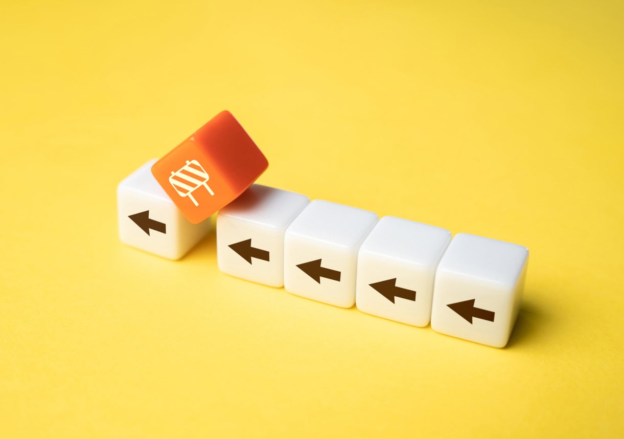 A row of dice with arrows on each pointing in the same direction but along the way is an orange dice with a symbol of a barrier, it is hanging between two of the dice breaking the chain of arrows.