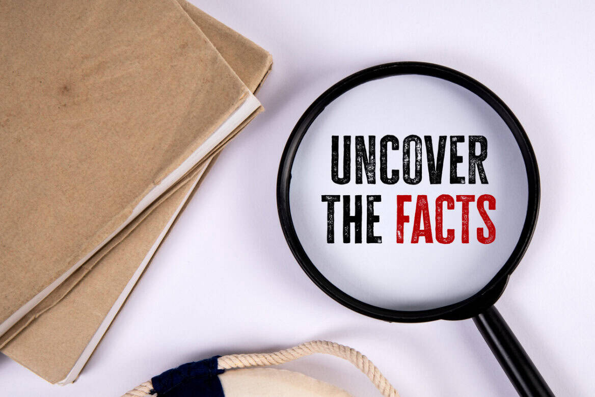 Uncover the facts. Magnifying glass and stack of books on white table.