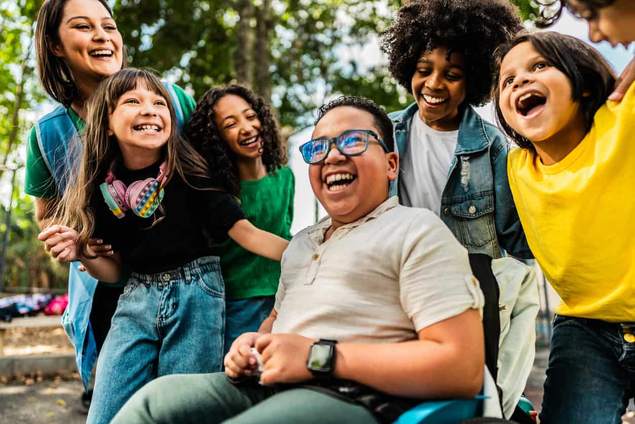 Happy students on schoolyard- including a wheelchair boy