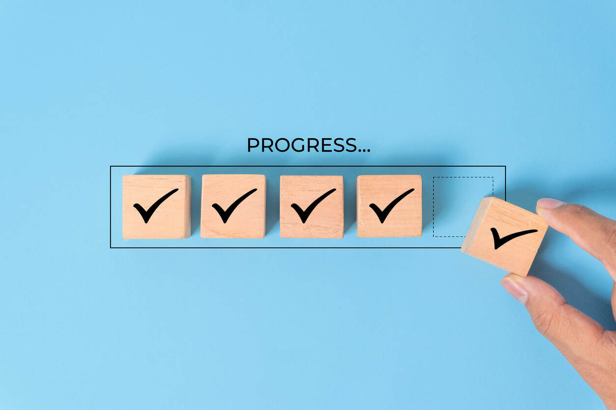 Checklist and task progress tracking concept. A hand placing the final checkmark on wooden blocks in a progress bar, task completion, productivity, goal setting, and efficient project managemen