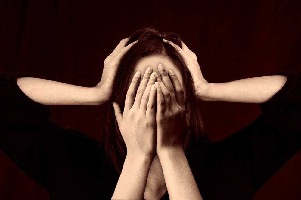 A woman with her hands covering her face like she is upset